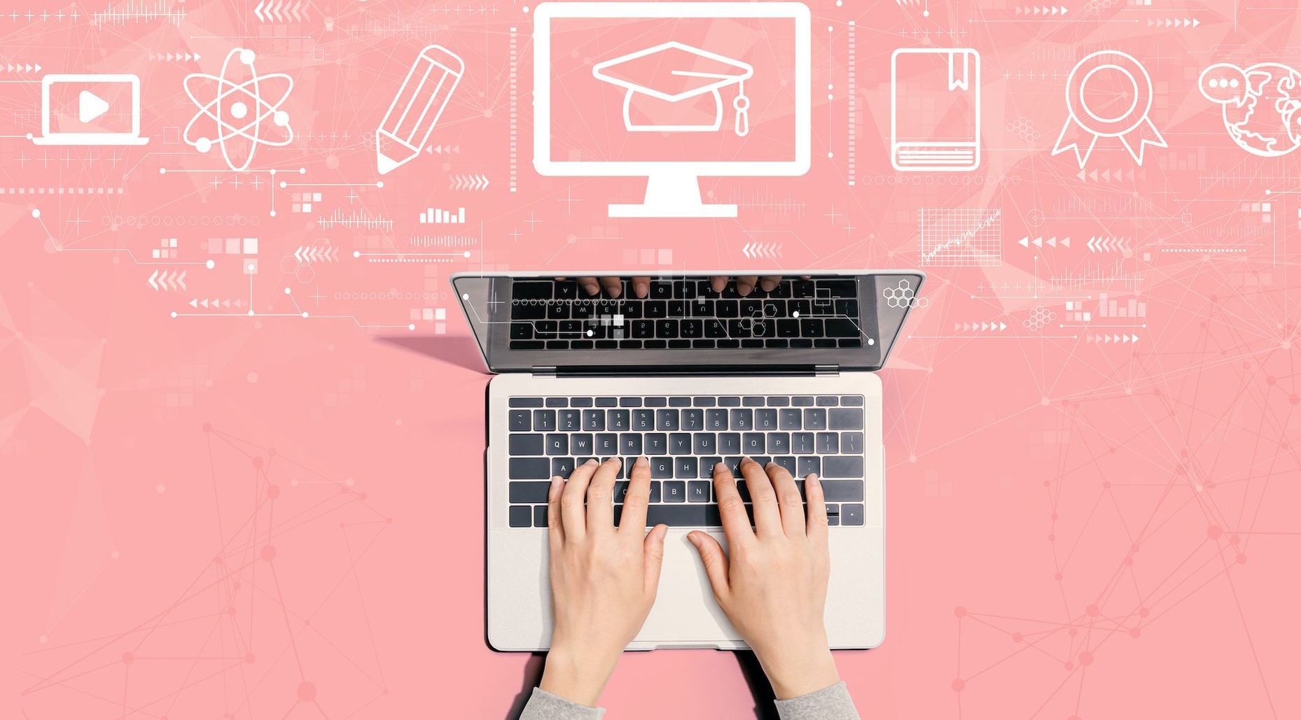 A person is typing on a laptop computer on a pink background.