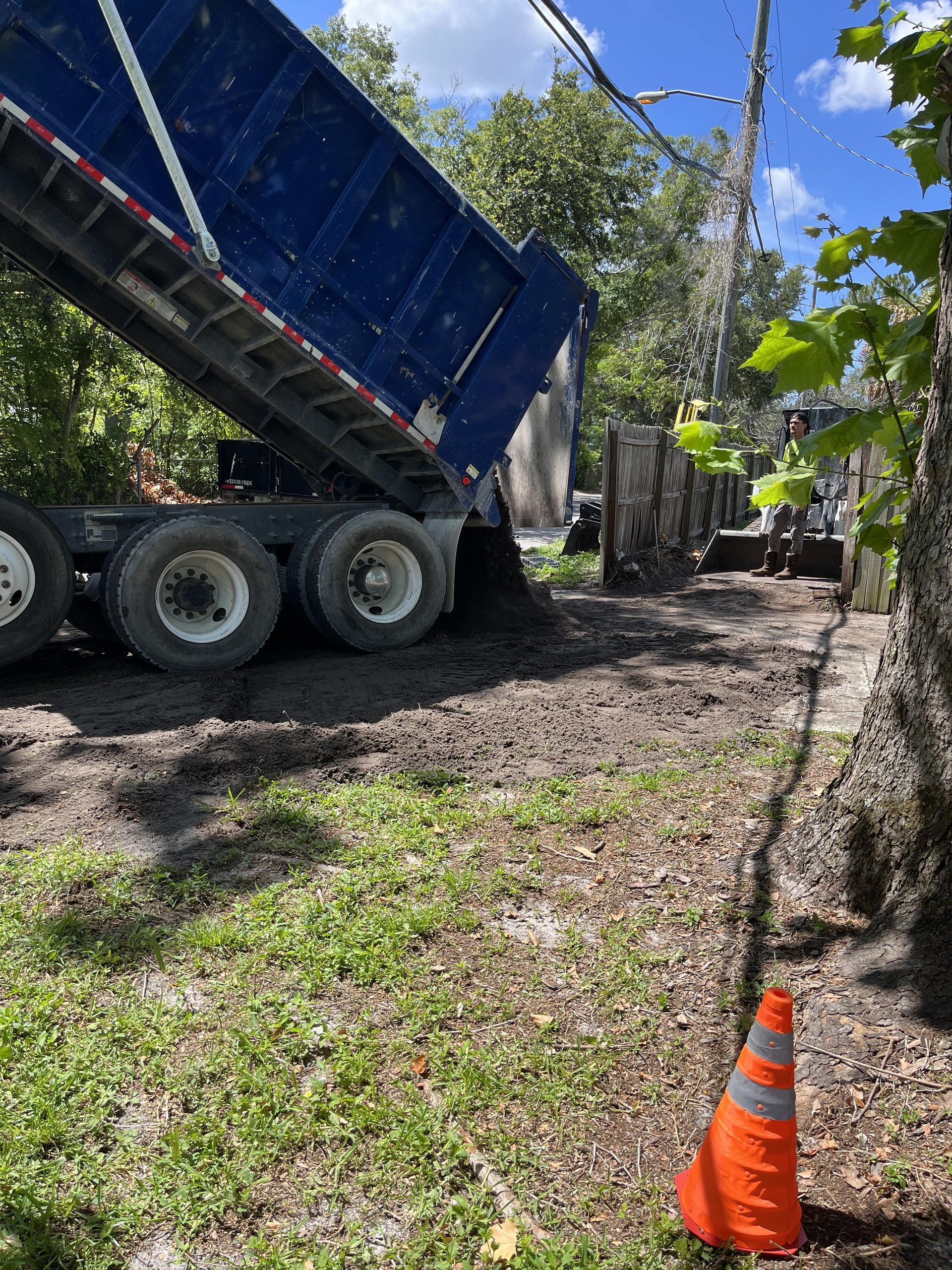 dump truck unloading about 10 cubic yards of dirt into driveway