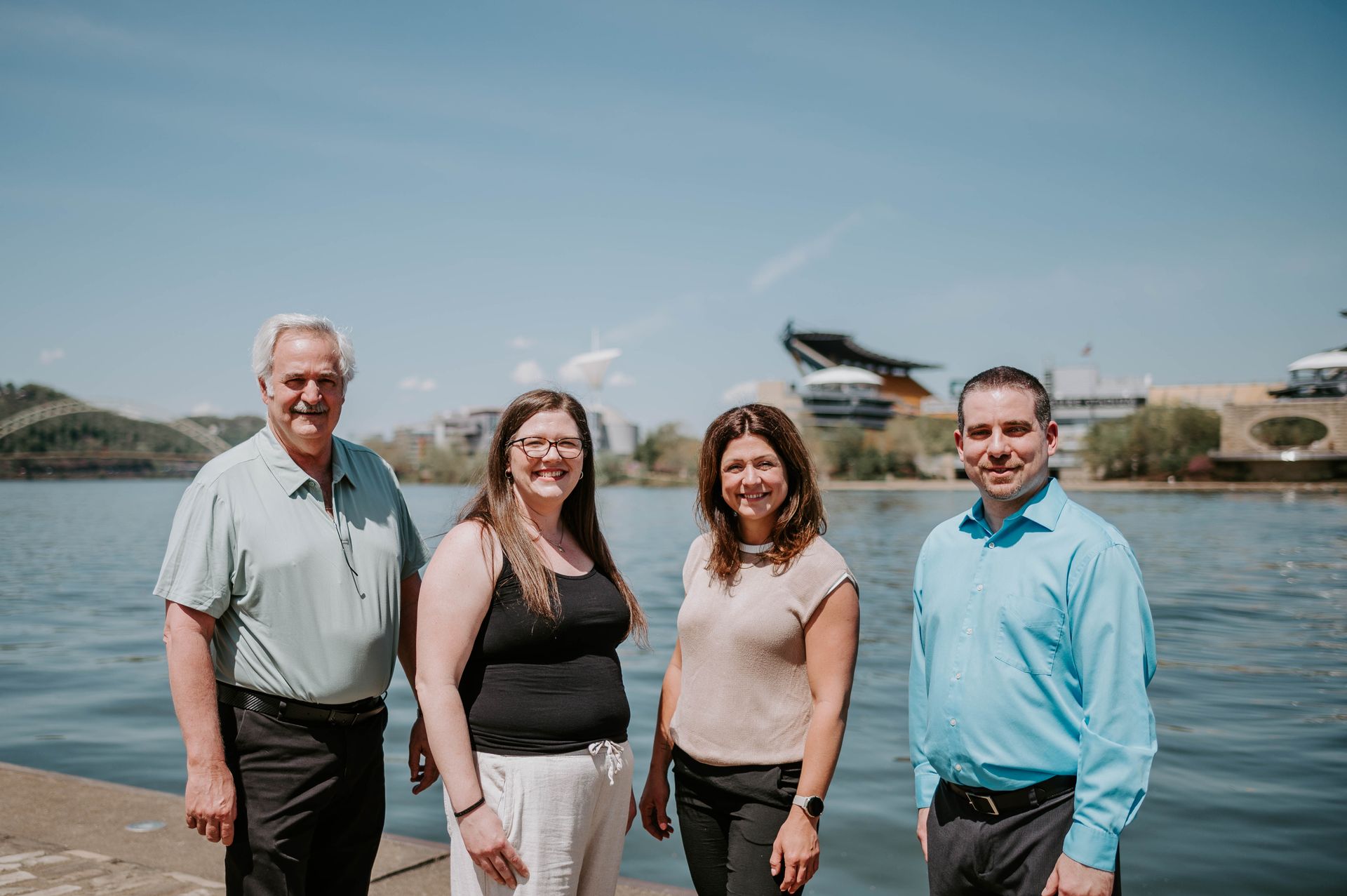 Four people standing by a waterfront with a helicopter in the background.