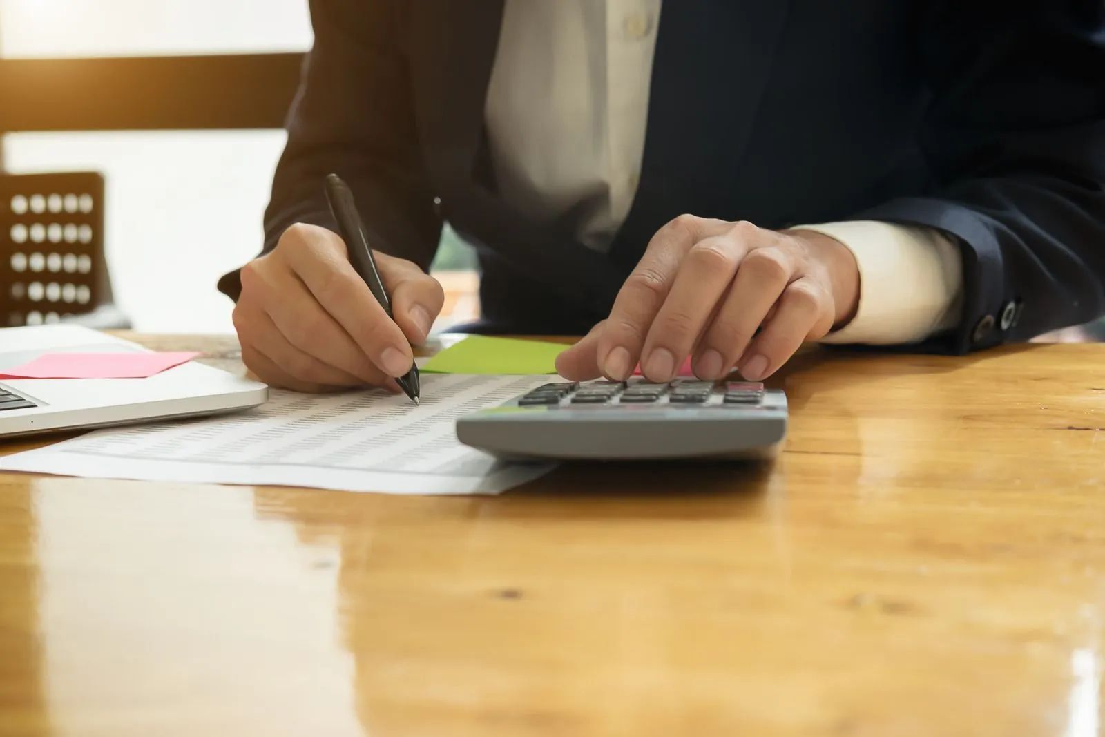 Person writing on paper beside a calculator at a desk