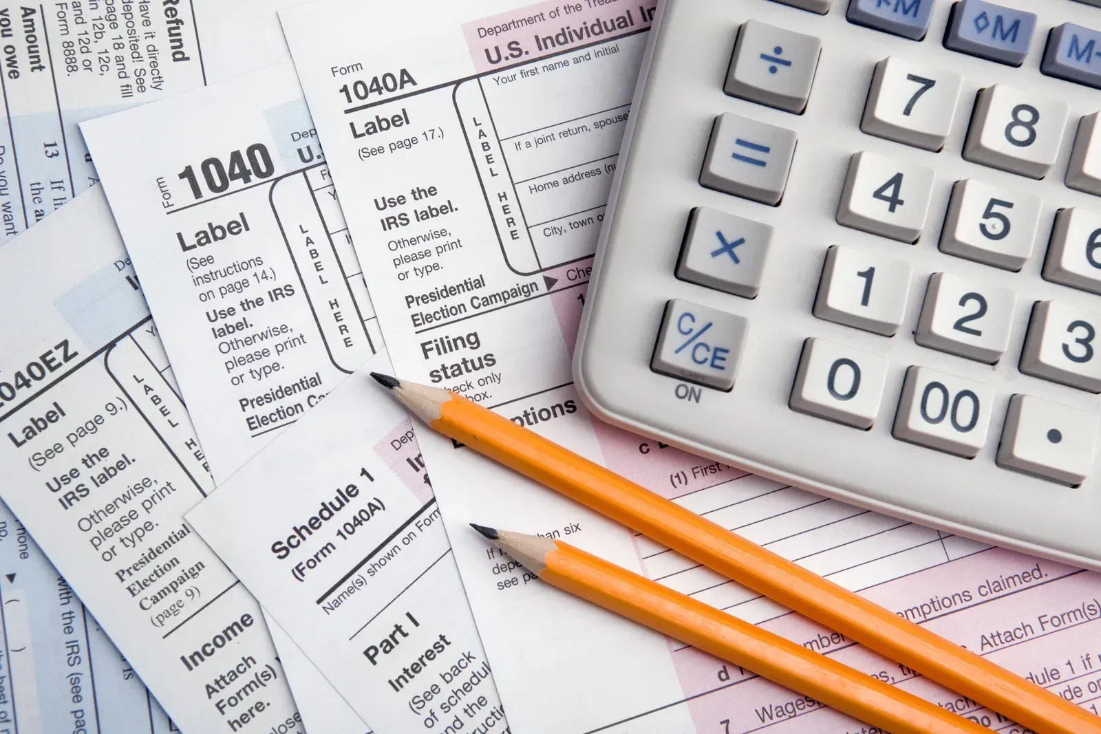 Calculator, tax forms, and two pencils on a desk for financial planning