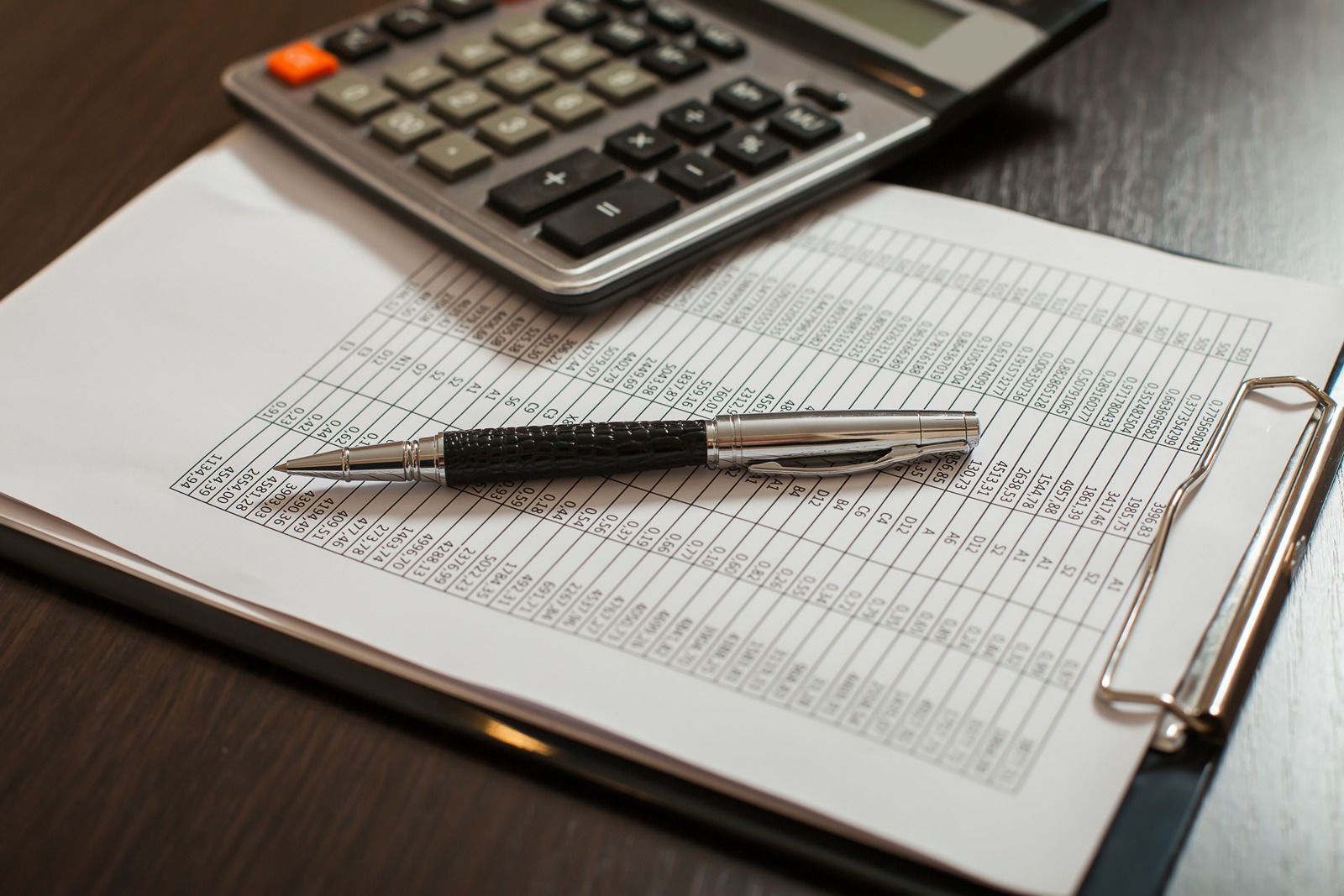 Calculator, pen, and ledger on a desk, suggesting accounting or bookkeeping.