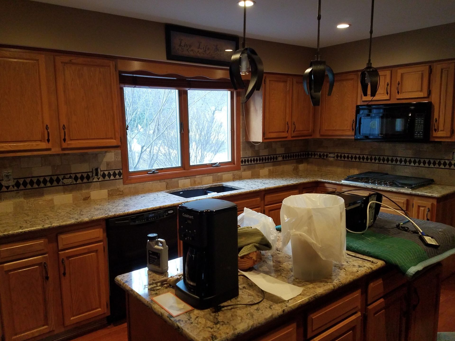 A kitchen with wood cabinets, granite countertops, and a central island with a coffee maker.