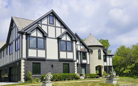 Tudor-style house with black and white exterior, turret, and manicured lawn.