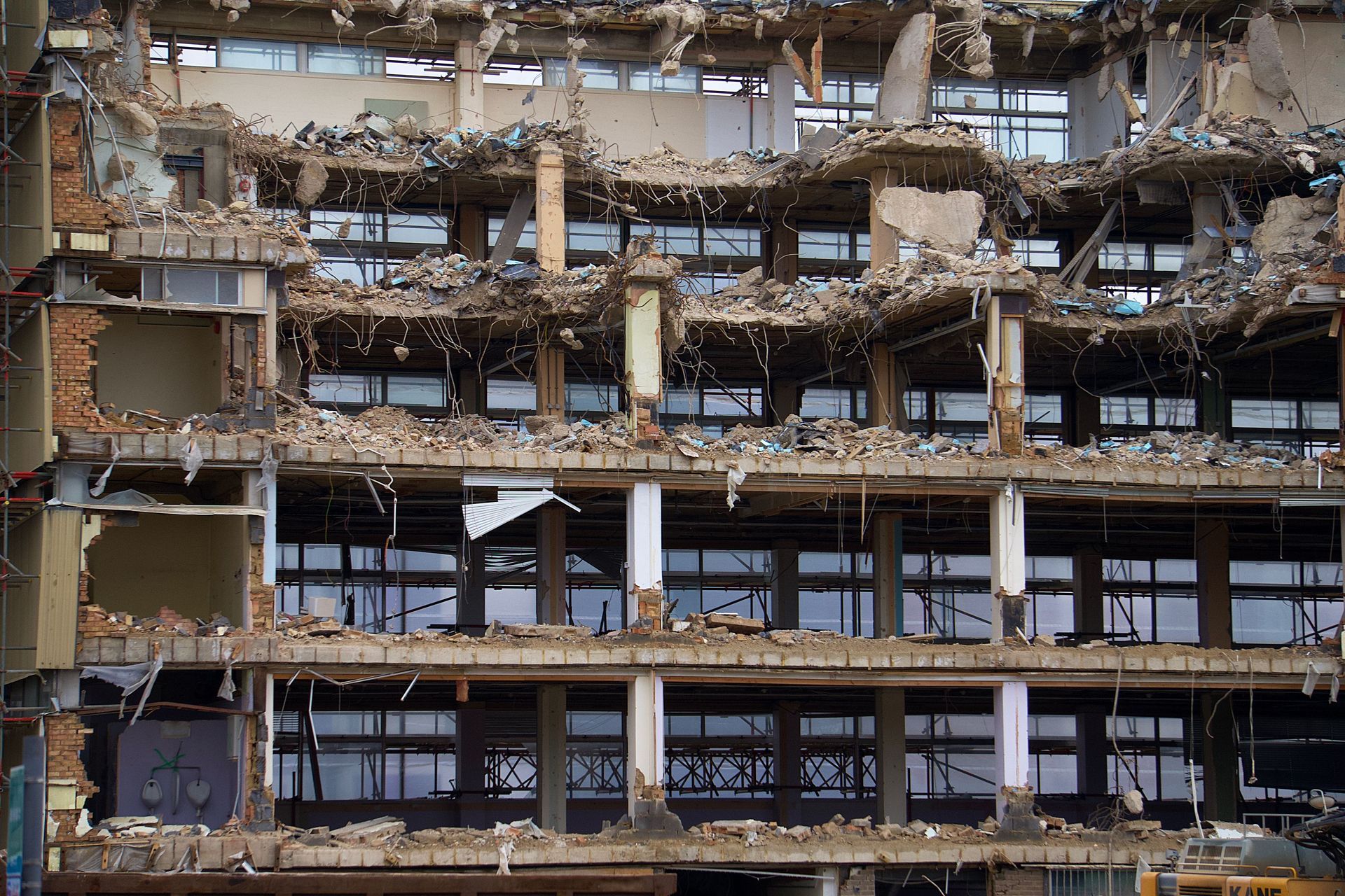 Collapsed multi-story building facade with exposed floors, rubble, and broken windows.