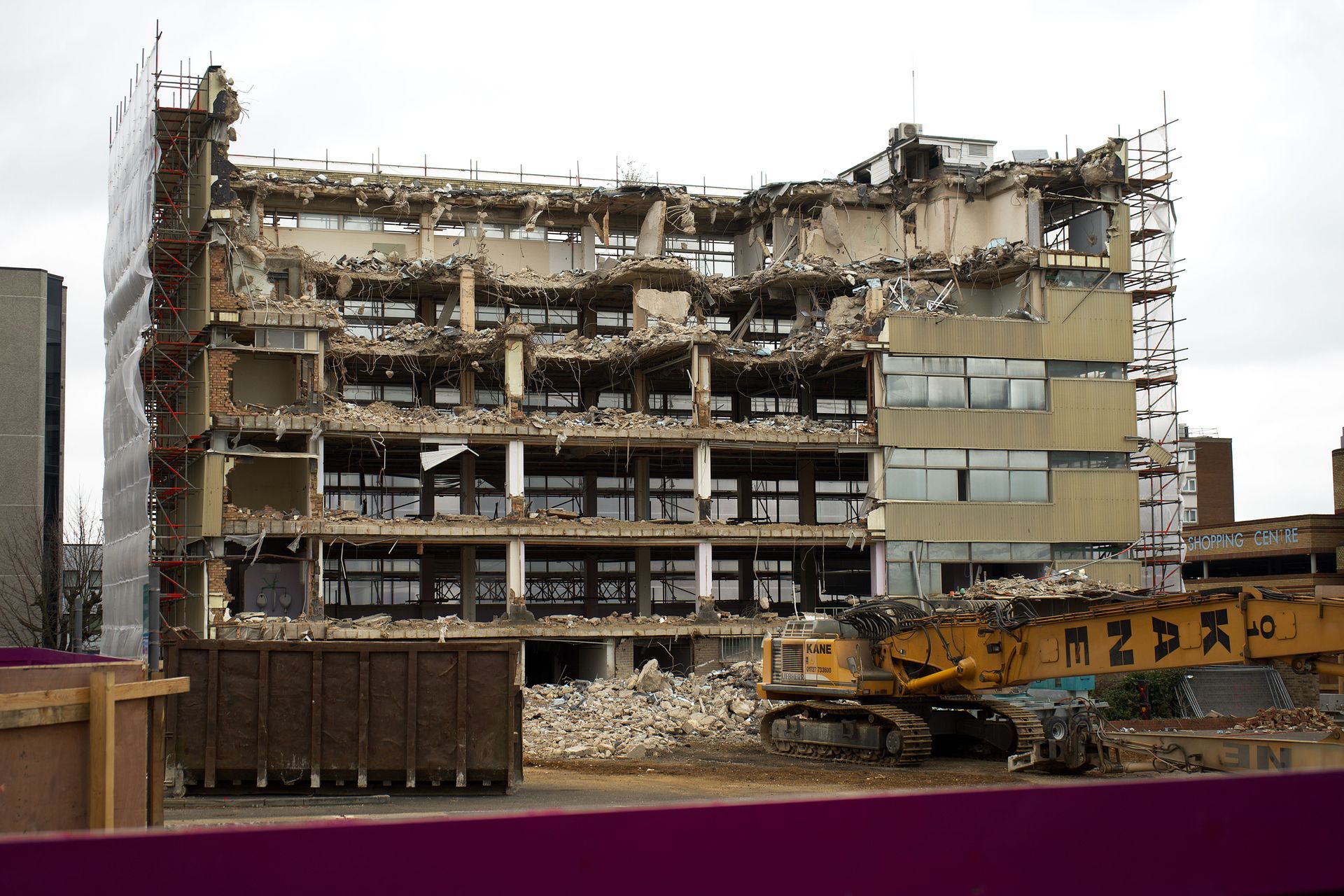 Partially demolished multi-story building with rubble and construction equipment in front