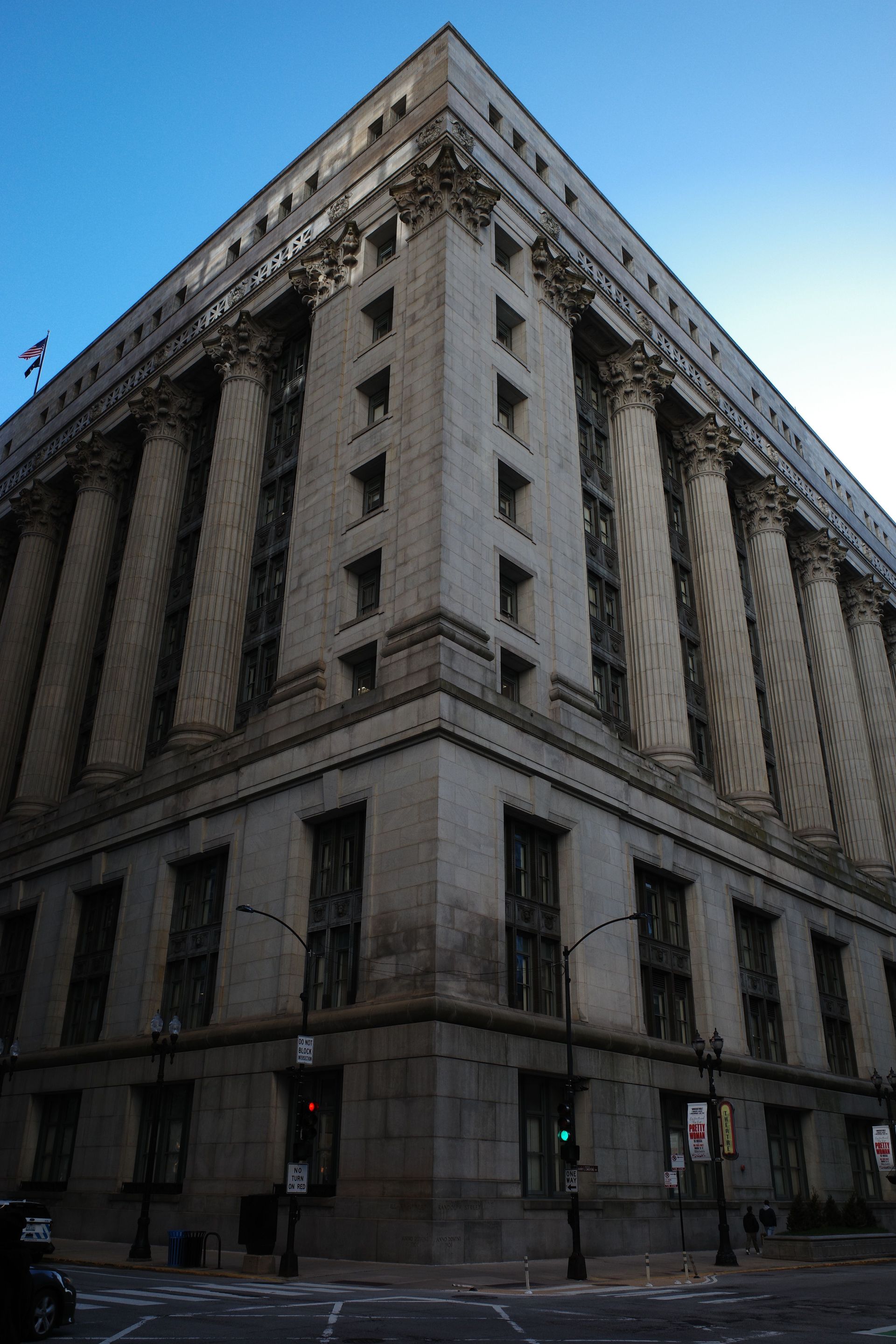Tall gray stone office building on a city street under a blue sky
