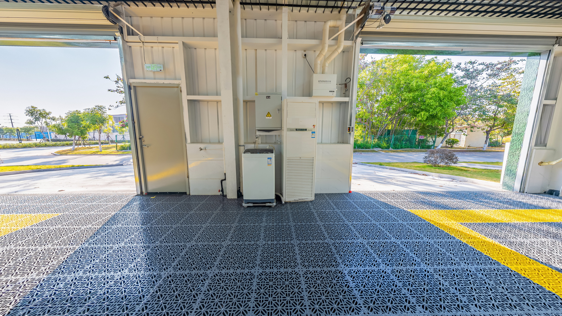 Open utility area with electrical cabinets, open door, and bright daylight outside