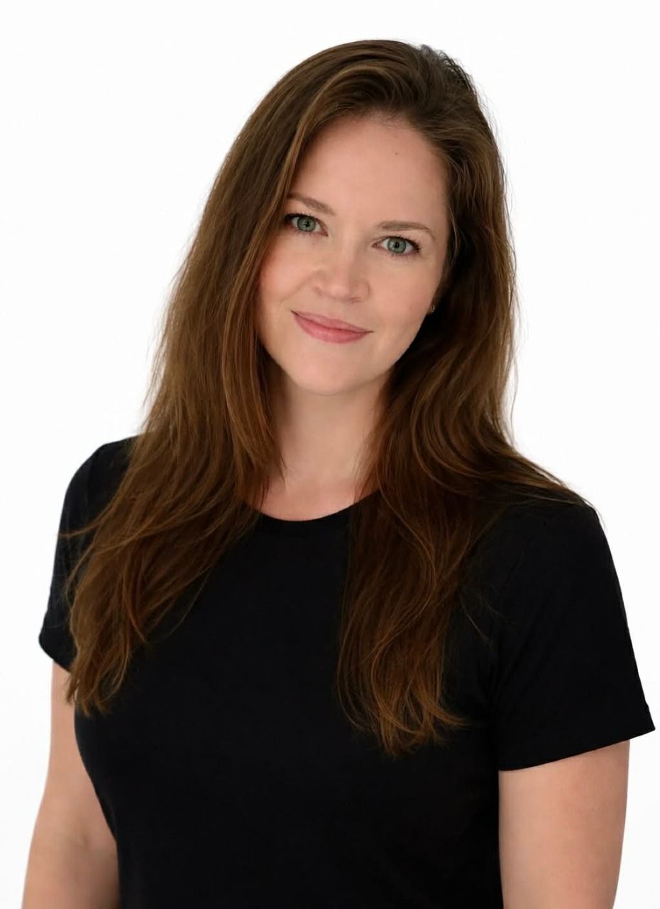Smiling woman with long brown hair wearing a black shirt against a white background