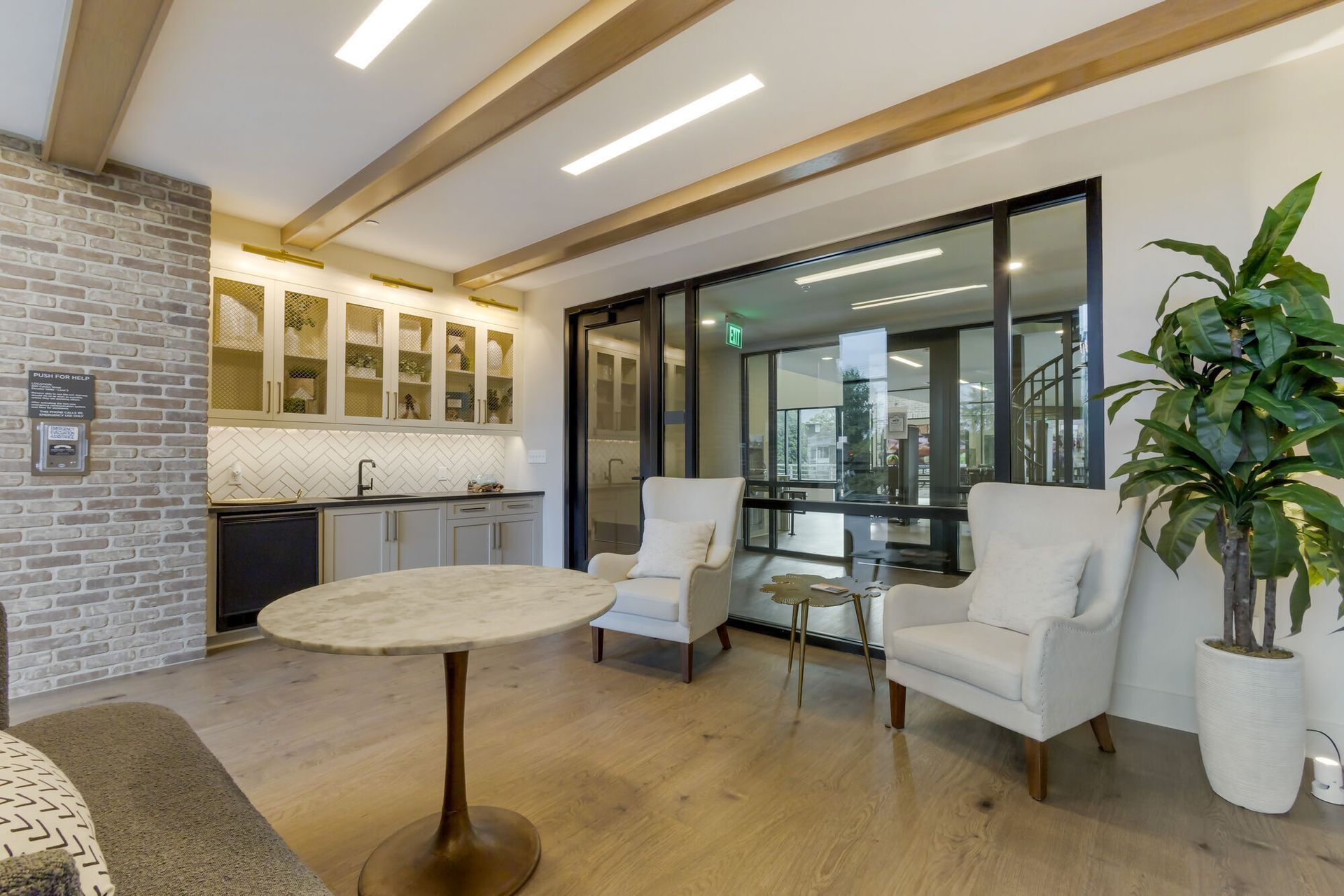 A modern lounge area with a small bar, seating, and large windows looking outside.