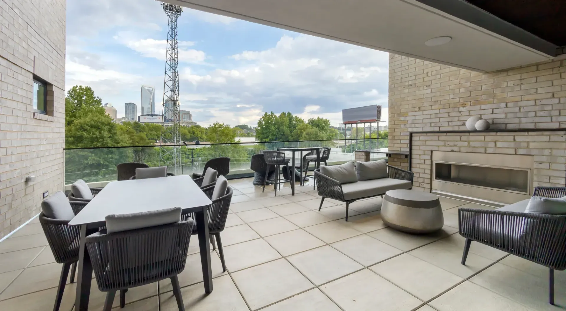 Outdoor rooftop terrace with modern seating, a fireplace, and city skyline view.