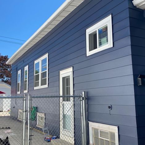 A blue house with a chain link fence around it A blue house with a chain link fence around it