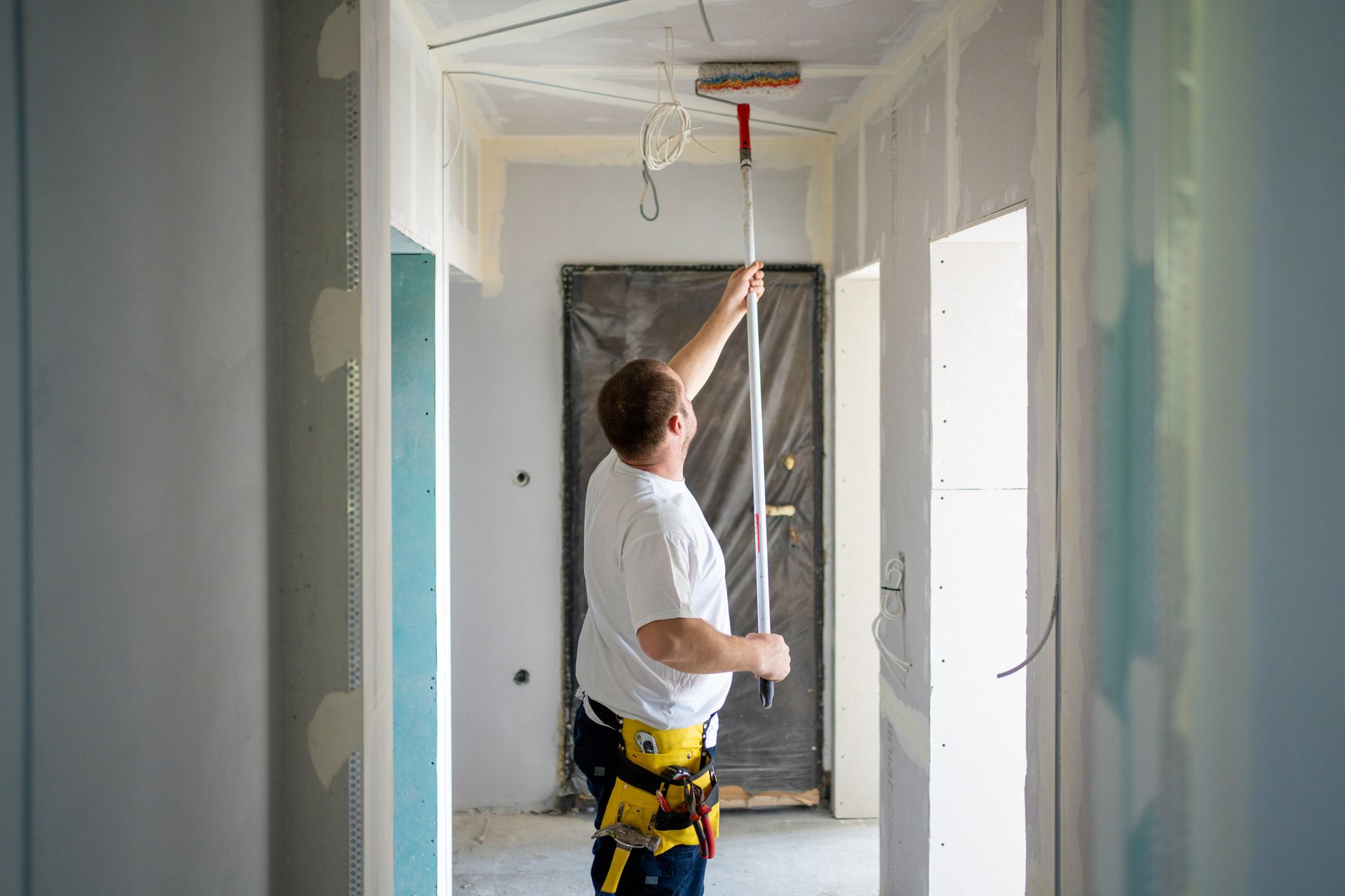A man is painting the ceiling of an apartment. A man is painting the ceiling of an apartment.