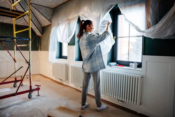 Woman is covering windows with plastic