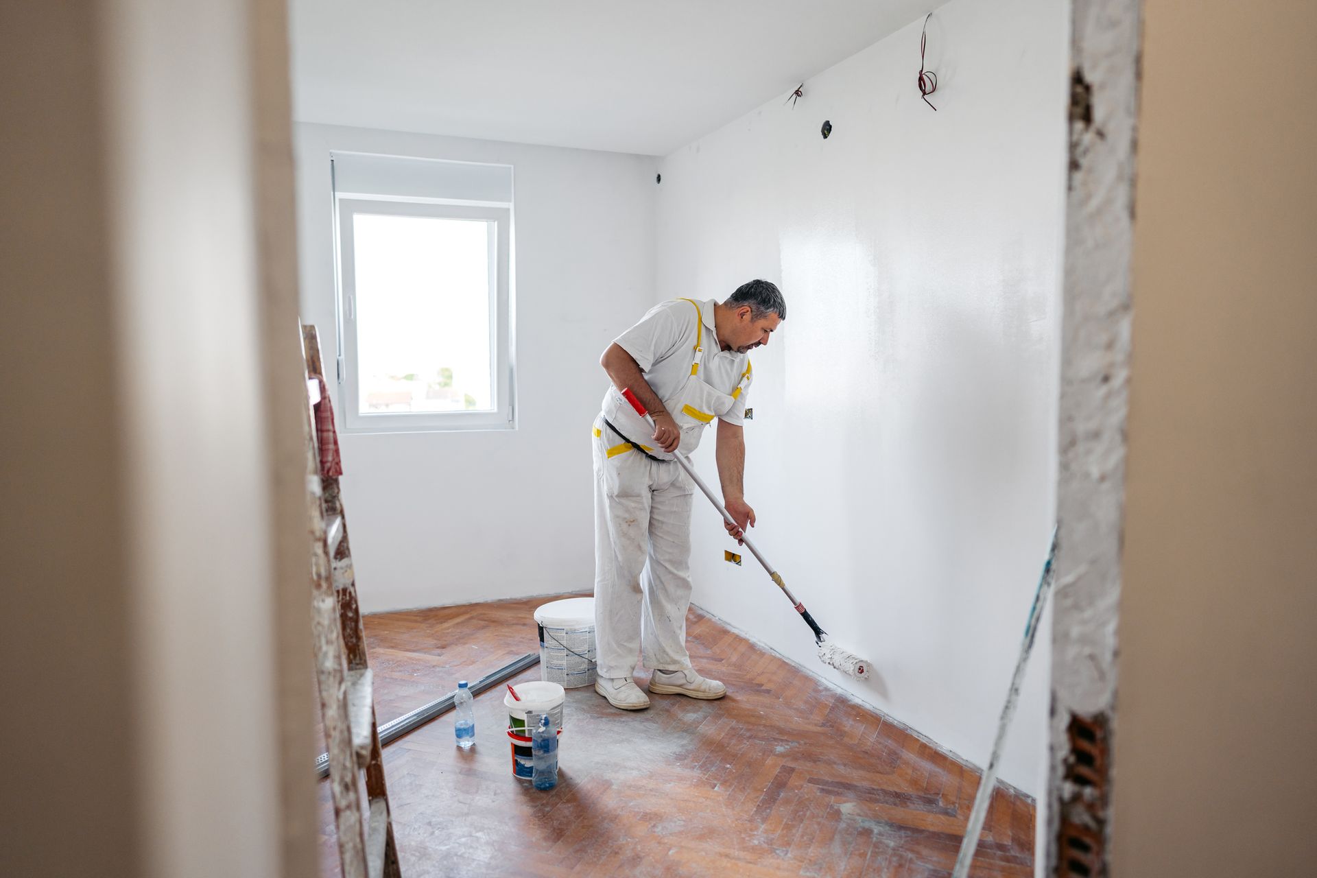 A worker is painting the walls with a paint roller. A worker is painting the walls with a paint roller.