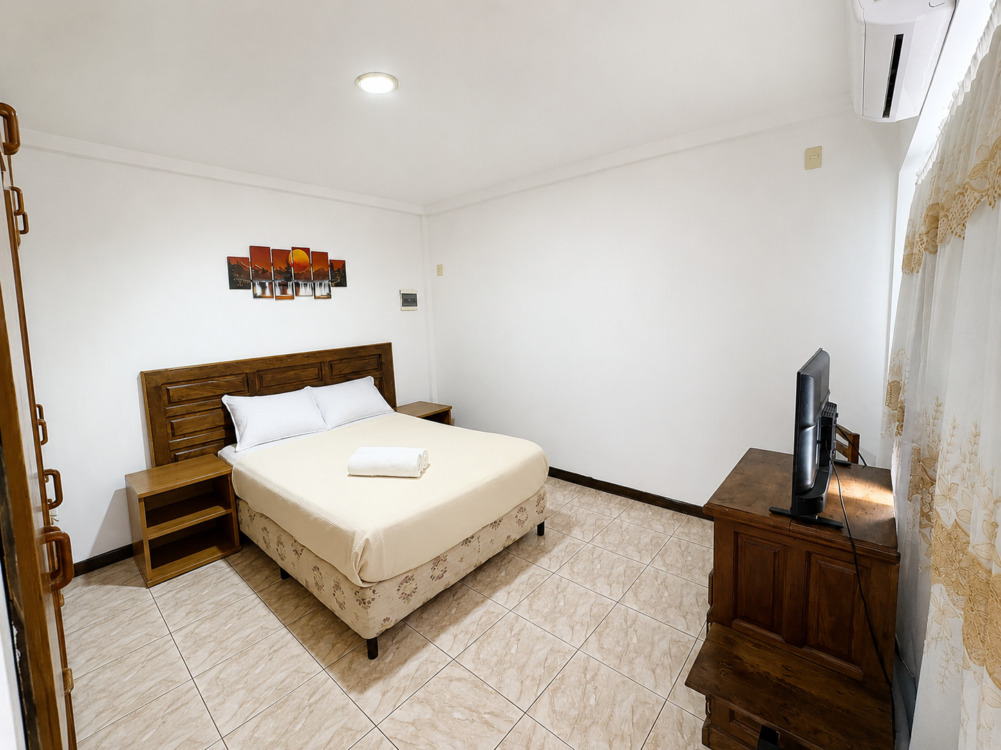 Small bedroom with a bed, wooden dresser, TV, and white tiled floor