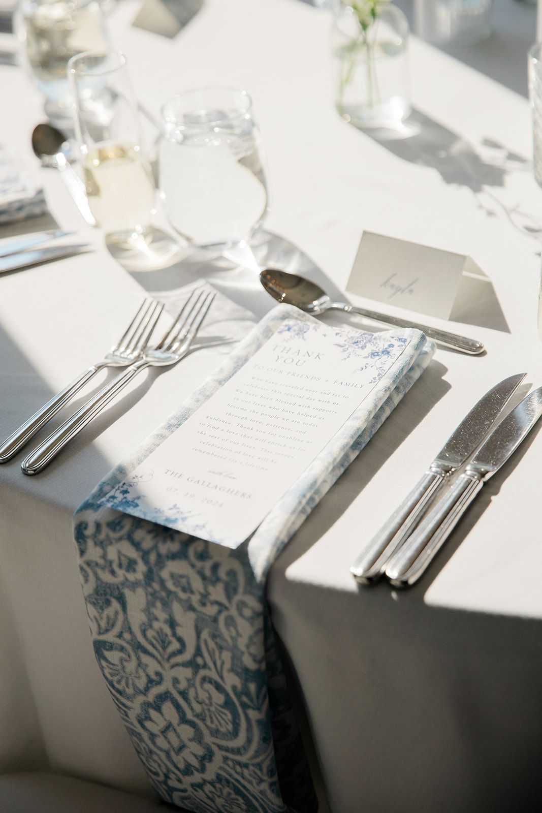 A white table with silverware and a menu on it at a luxury cape cod wedding.