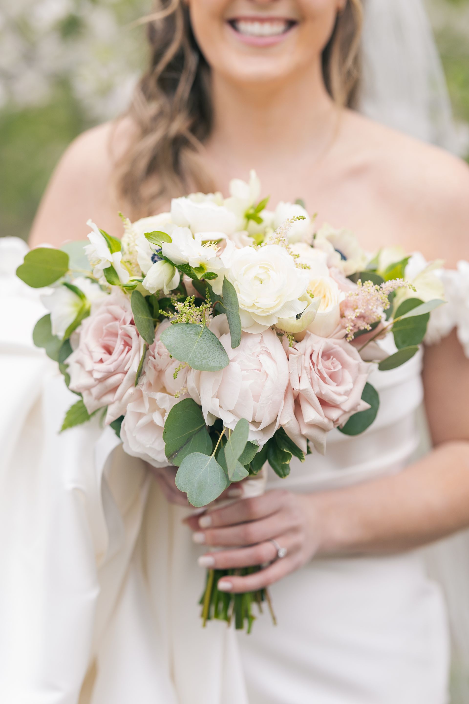 A bride in a white dress is holding a bouquet of pink and white flowers in Newport RI.