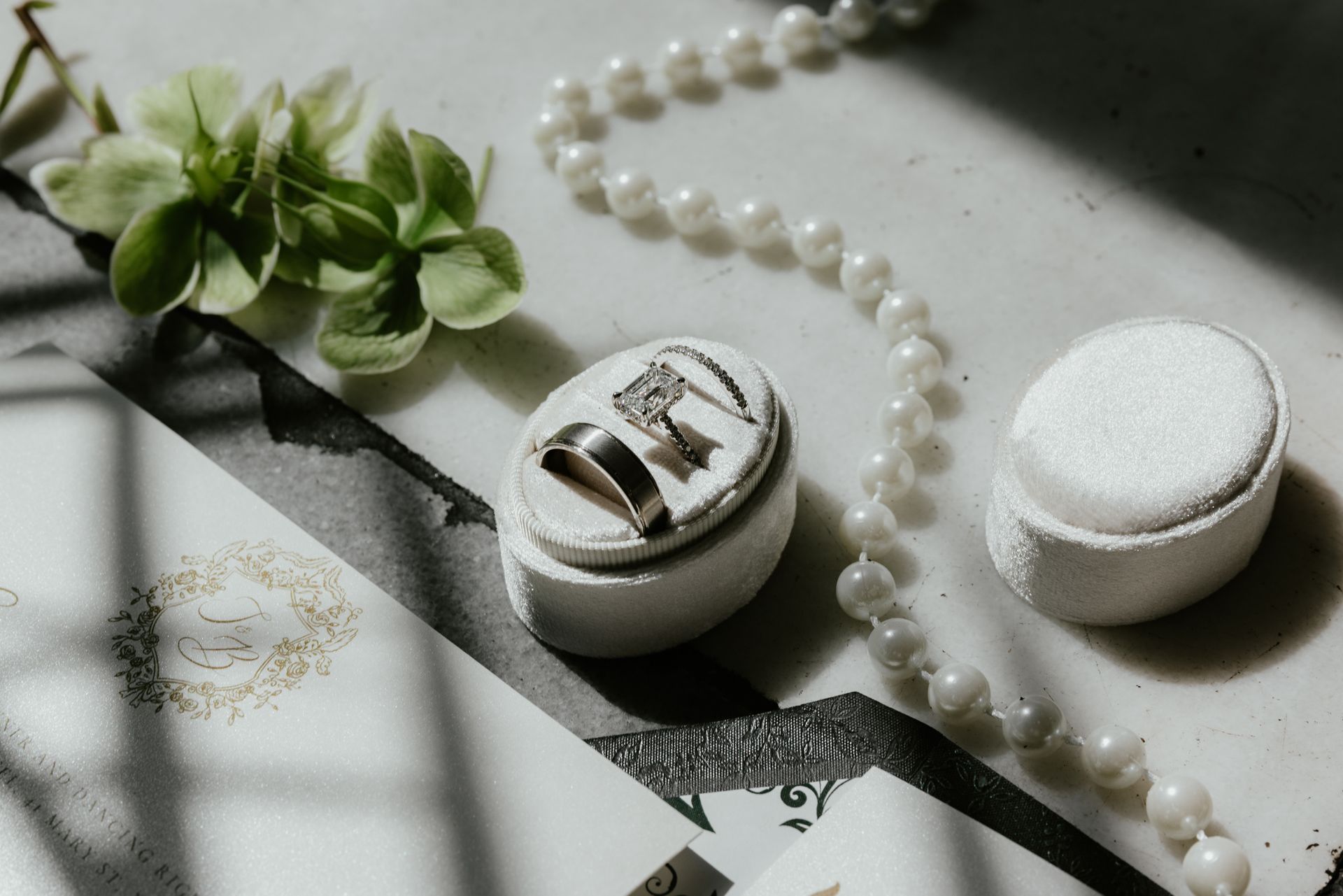 A pair of wedding rings and a pearl necklace are sitting on a table in a luxury hotel in Newport RI.