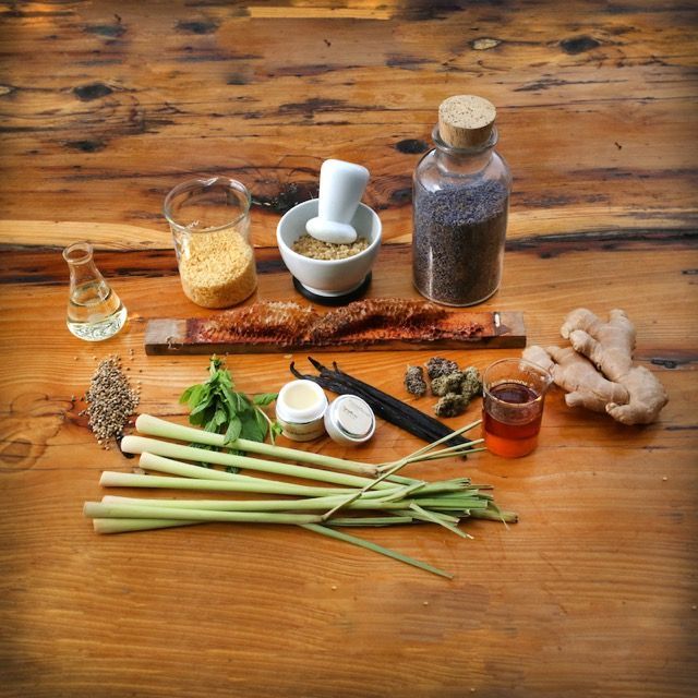 Herbs, ginger, spices, and glass bottles arranged on a wooden table for cooking or herbal prep