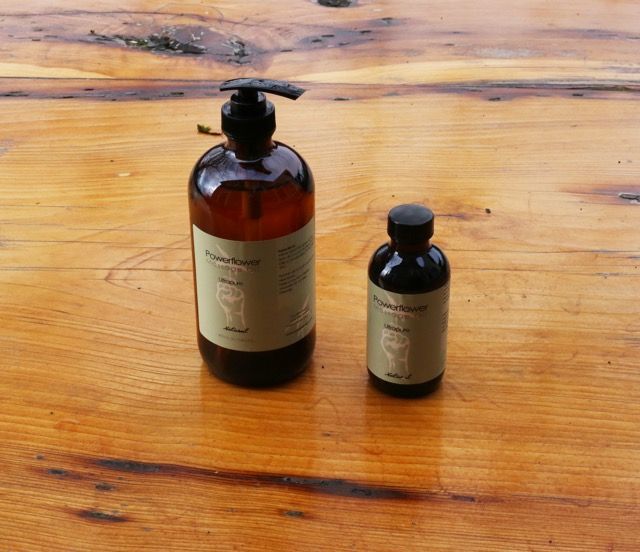 Two dark amber pump bottles on a wooden table, one large and one small.
