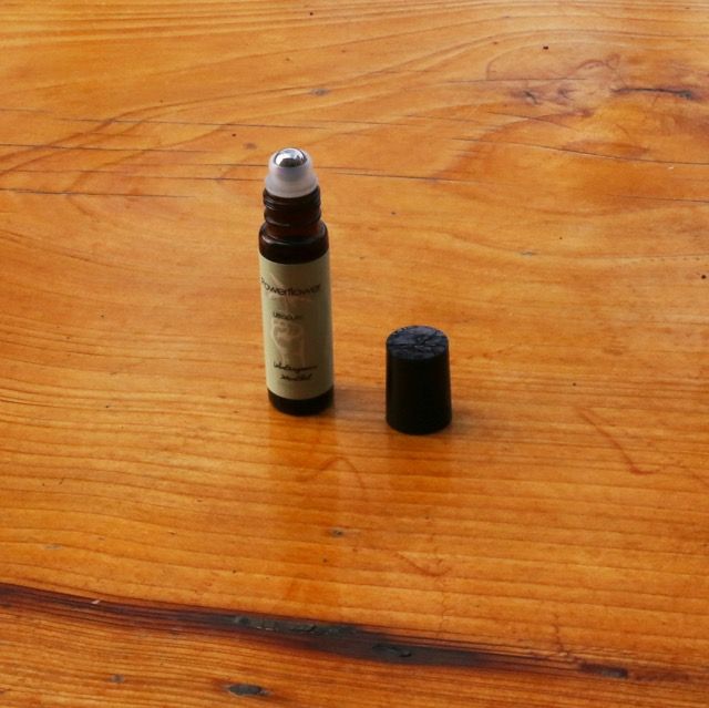 Small brown bottle with a black cap beside it, standing on a wooden table.
