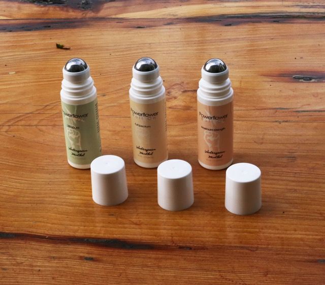 Three cosmetic spray bottles with white caps on a wooden table