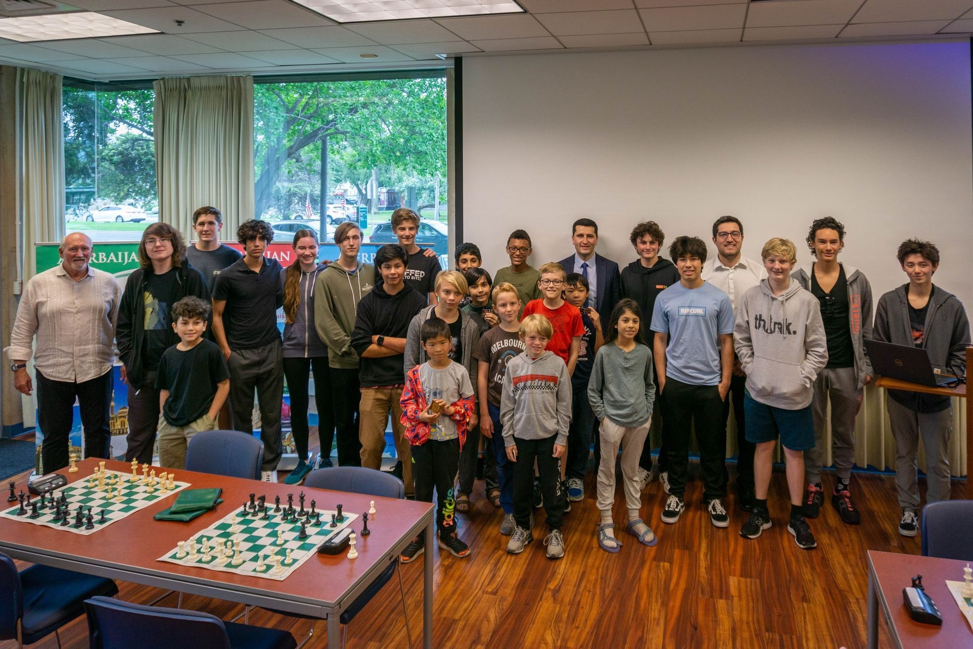 A group of people are posing for a picture in front of a table with chess pieces on it.