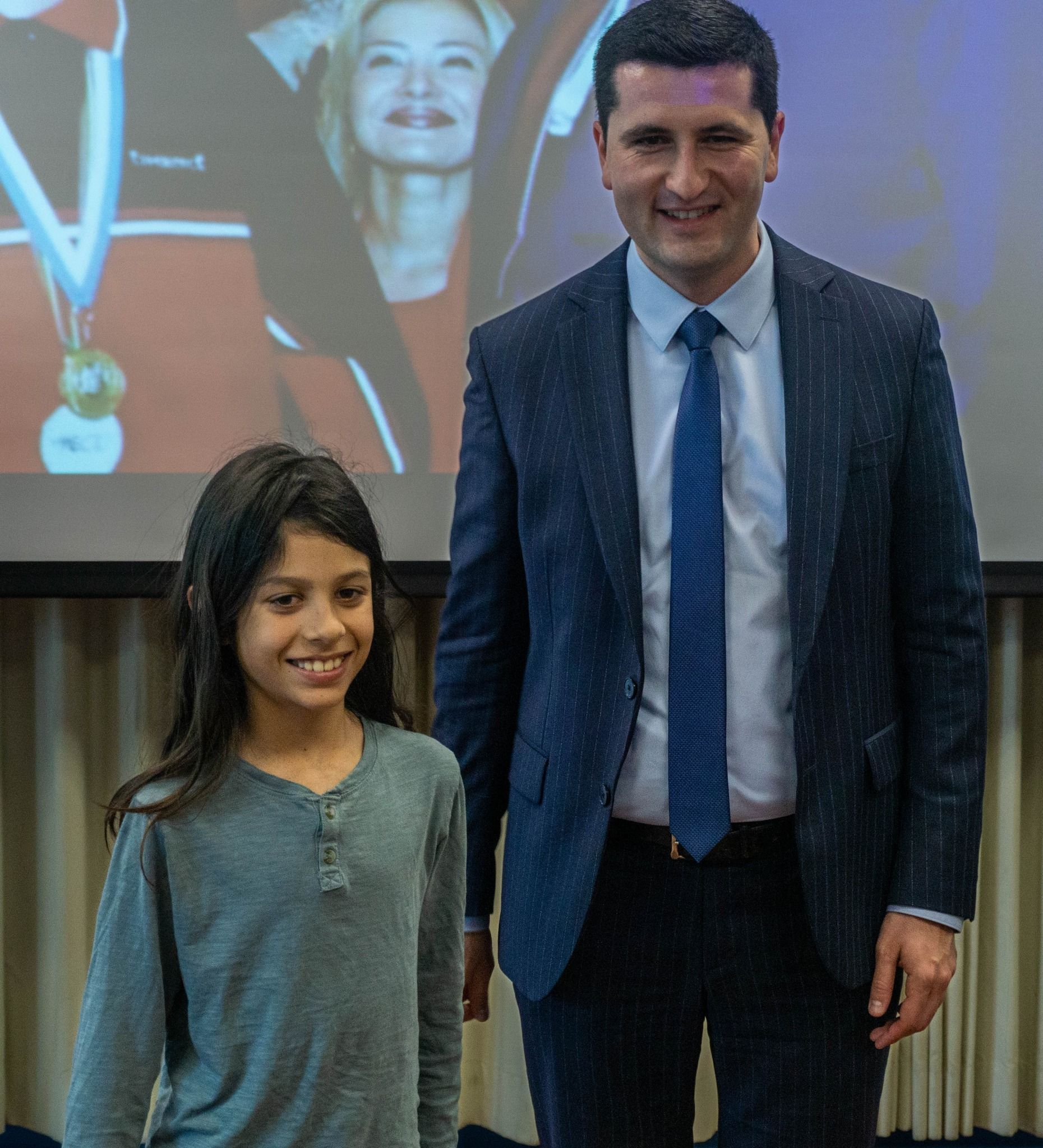 A man in a suit and tie stands next to a little girl