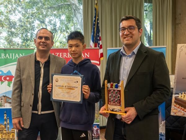 Three men are standing next to each other and one of them is holding a certificate