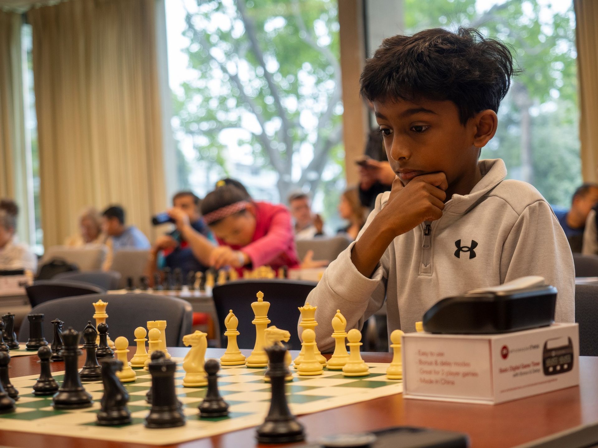 A young boy is sitting at a table playing chess.