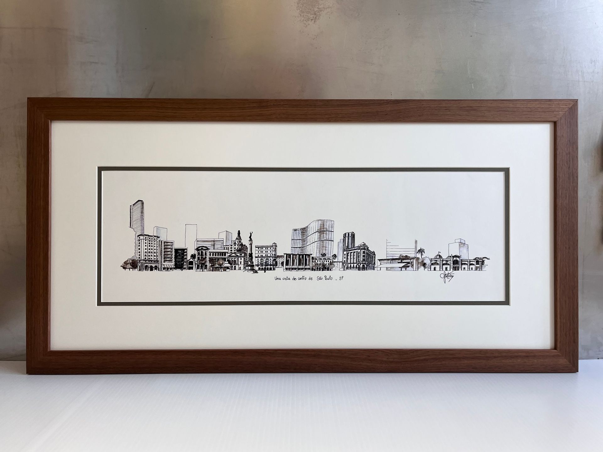 A black-and-white ink drawing of an industrial city skyline, professionally matted and framed in dark wood.