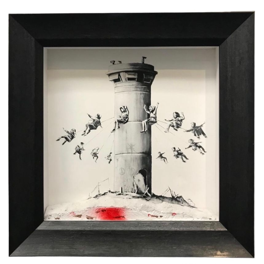 A Banksy artwork shows children on a fairground swing ride attached to a bleak, grey military watchtower.