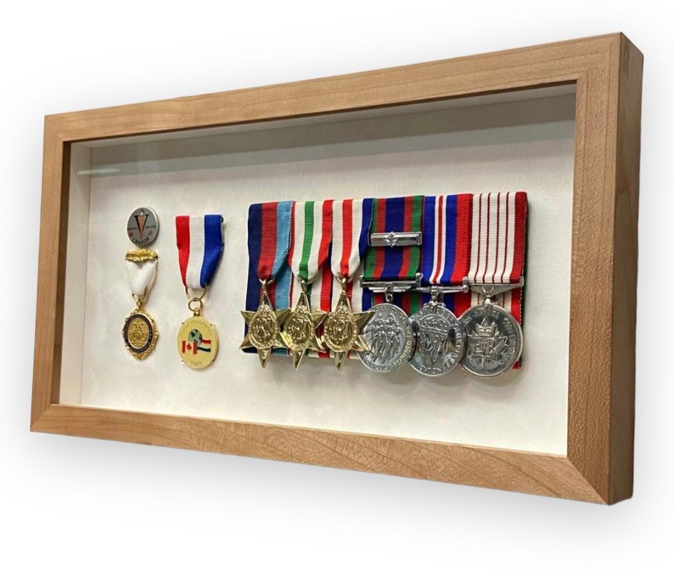 A collection of seven military medals mounted in a wooden shadow box frame against a plain white background.