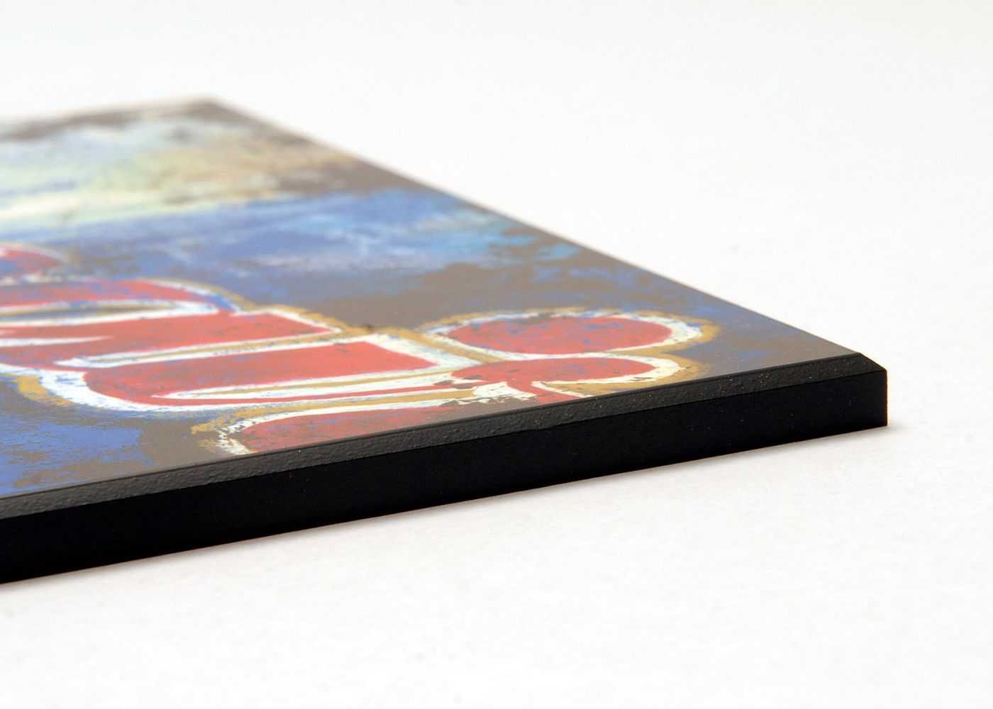 A close-up, angled view of a rectangular plaque with a printed graphic and a thick black edge on a white background.