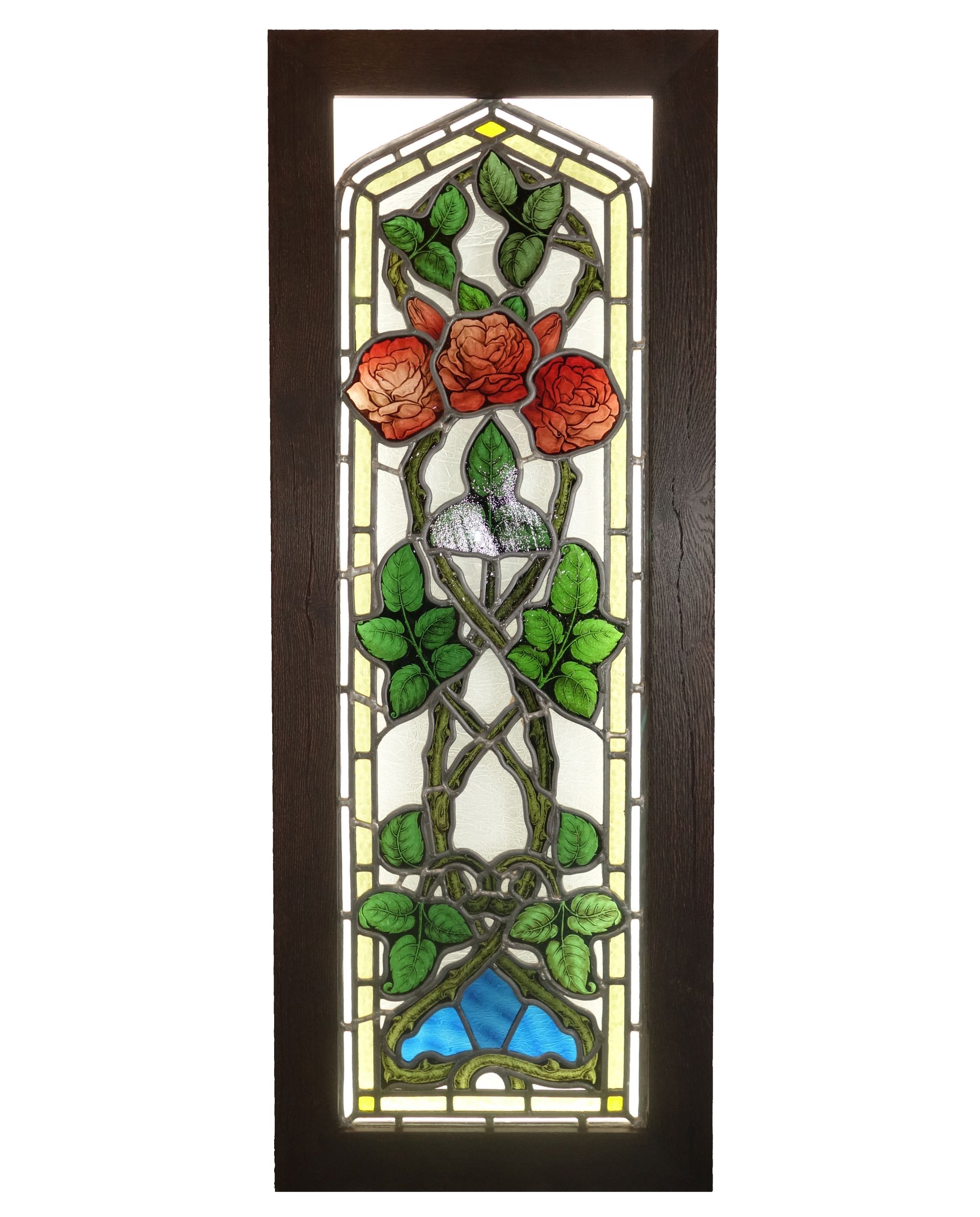 Stained glass window panel featuring red roses, green leaves, and a blue base inside a dark wooden frame.