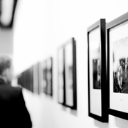 A person views a series of framed black-and-white photographs hanging in a gallery.