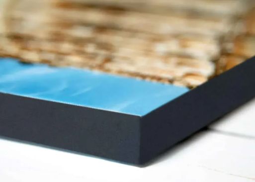 A close-up, angled view of a canvas print featuring a sandy beach, finished with a smooth black border.