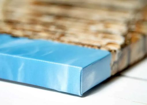 A close-up of a blue, rectangular block with a marble-like texture placed against a background of stacked wood.