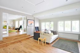 Bright living room with light wood floor, sofa, rug, desk, and windows.