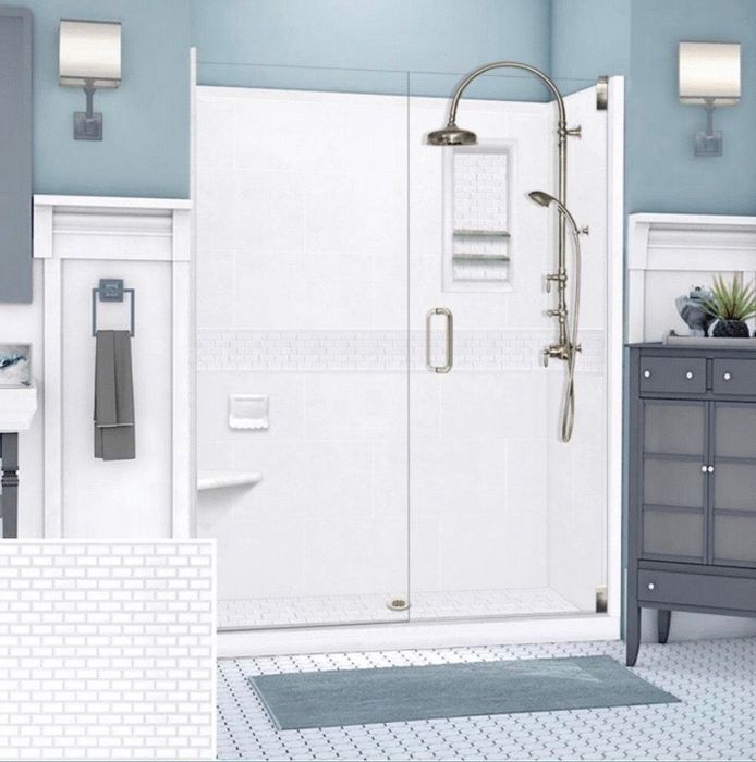 A white, tiled shower with glass doors in a blue-toned bathroom with a shower head and hand-held shower.