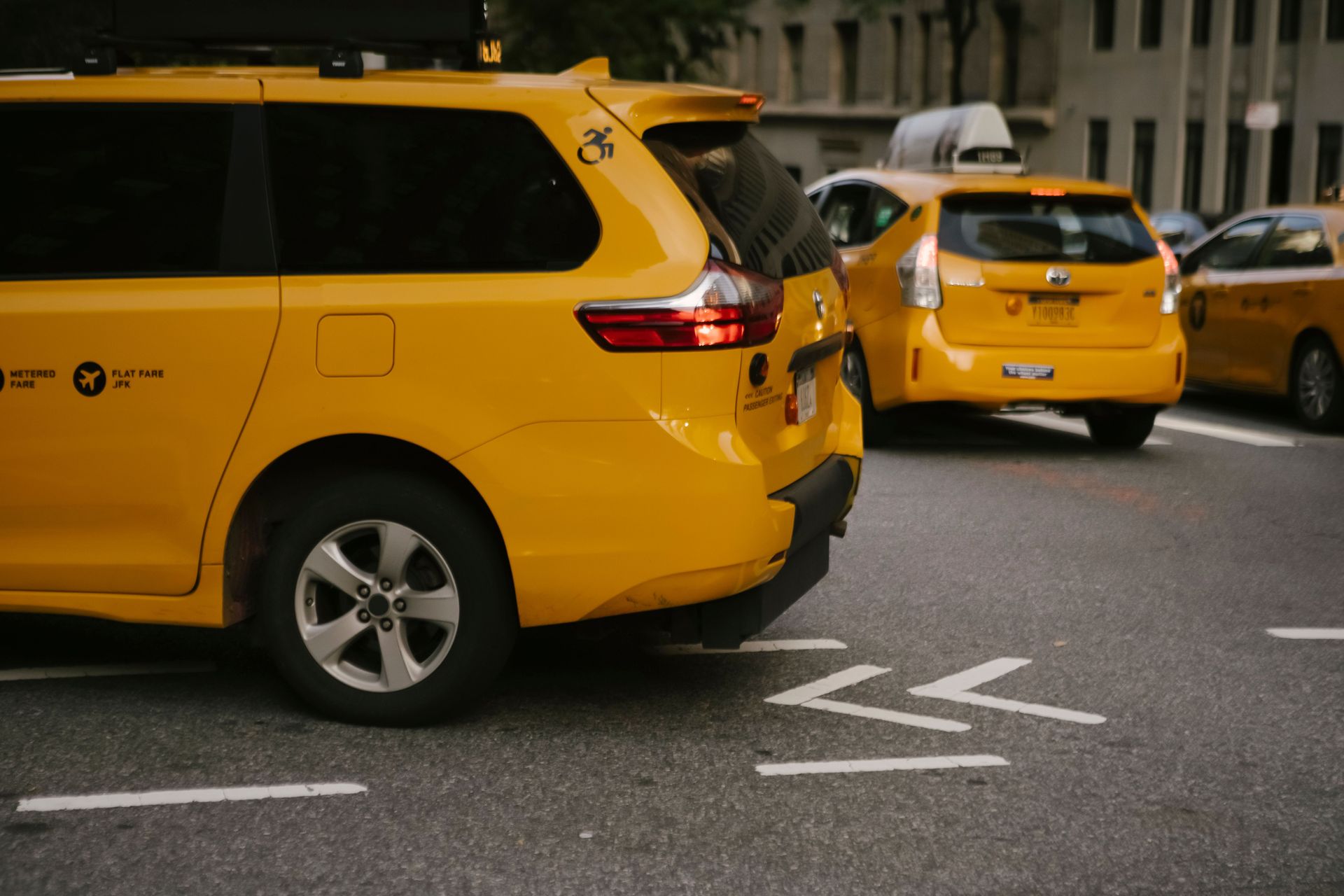 Yellow taxis lined up on a city street, with one taxi in the foreground.