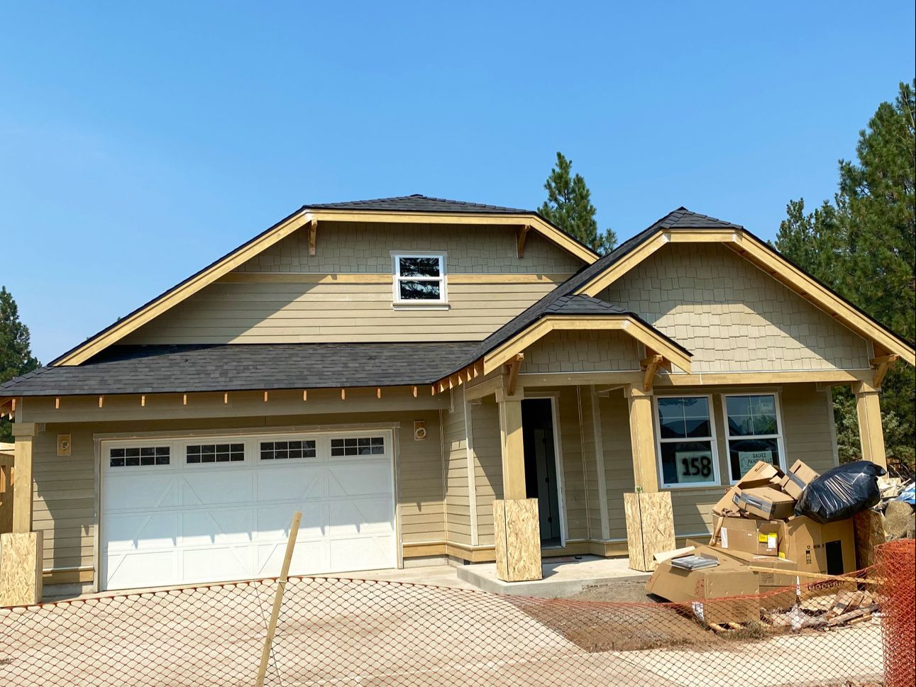 New beige suburban house with a two-car garage and a partially paved front yard