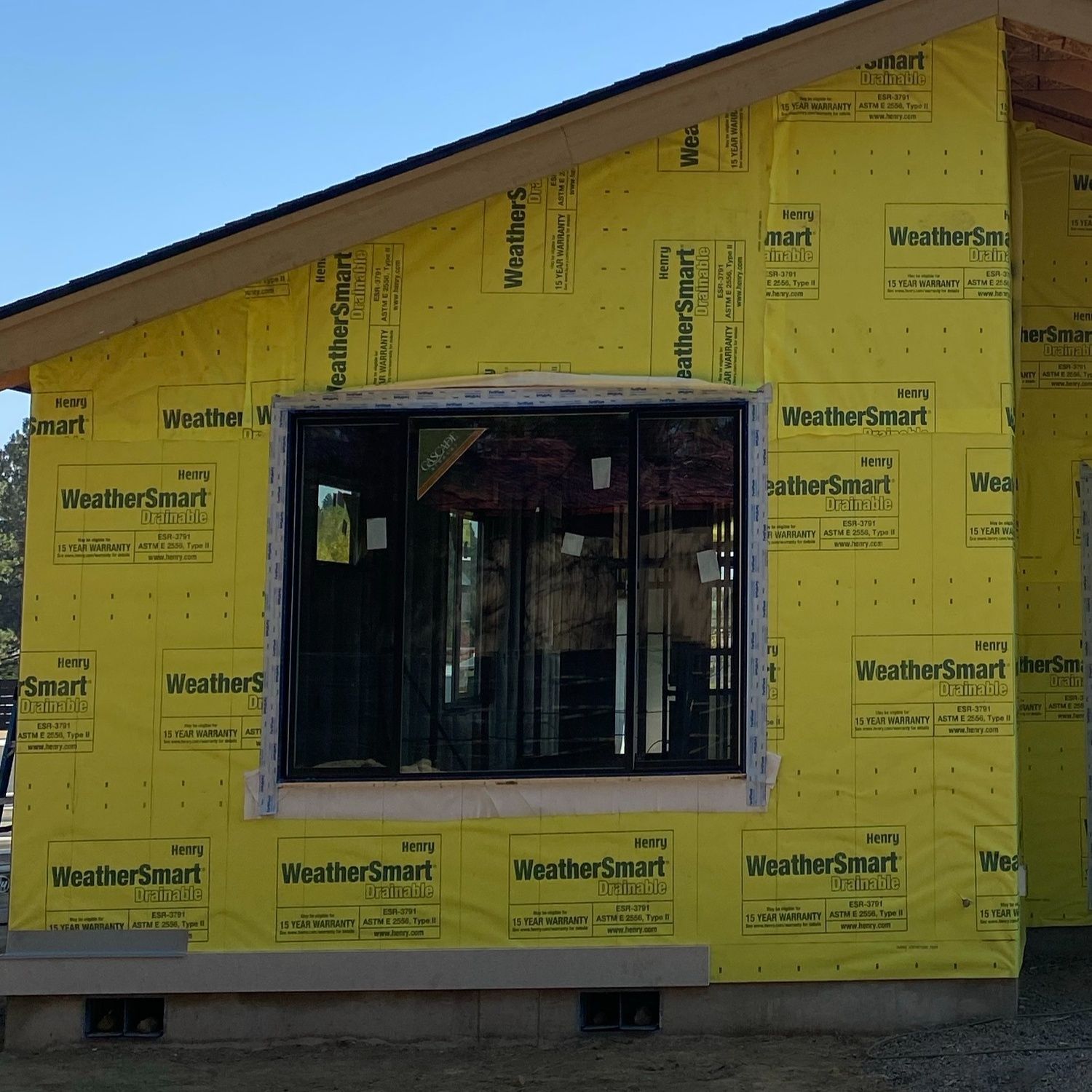 Yellow house under construction with a window opening and WeatherSmart wrap on the exterior
