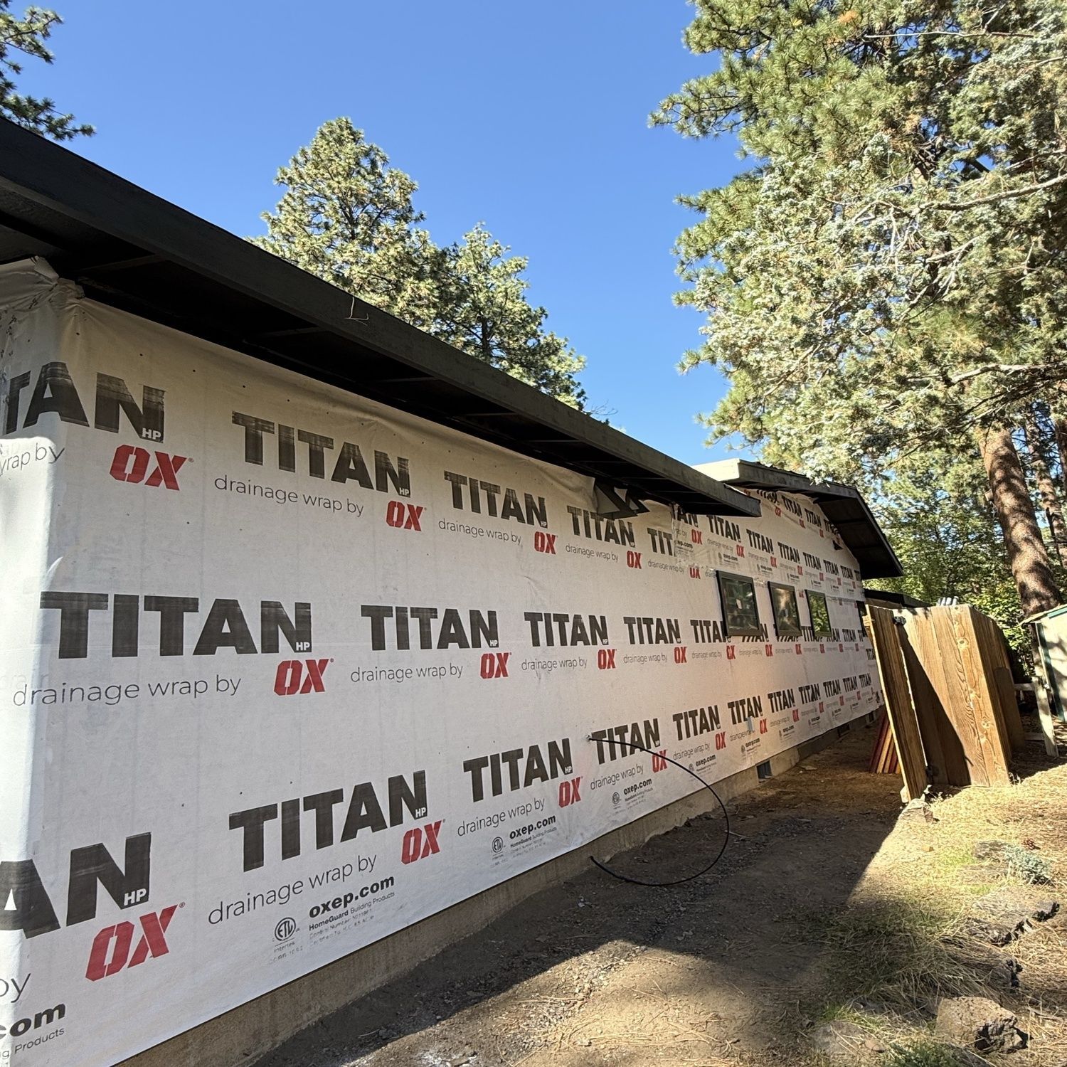 House under construction wrapped in Titan DX house wrap beside tall trees and blue sky