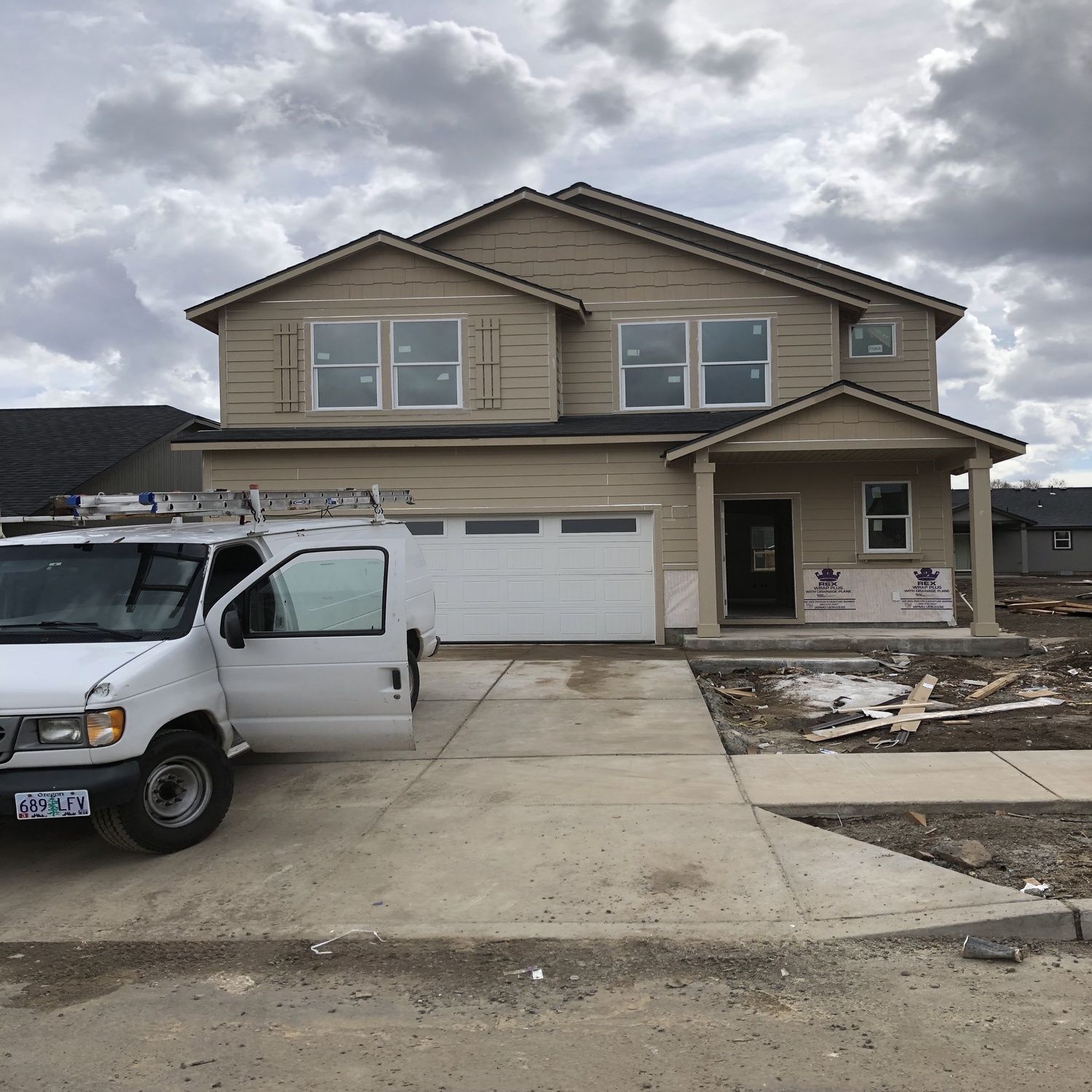 Suburban two-story house with a white van parked in the driveway and a cloudy sky overhead