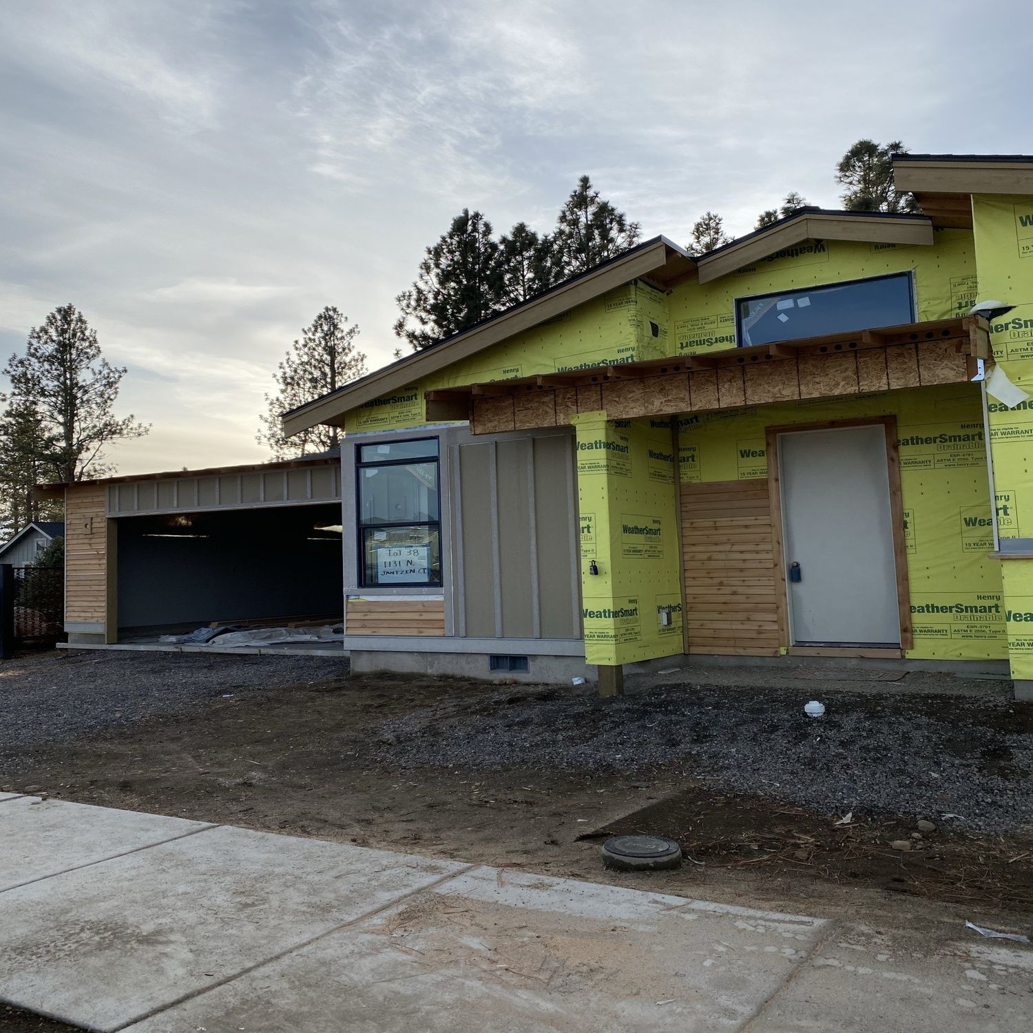 Partially built yellow house with garage and bare ground in front