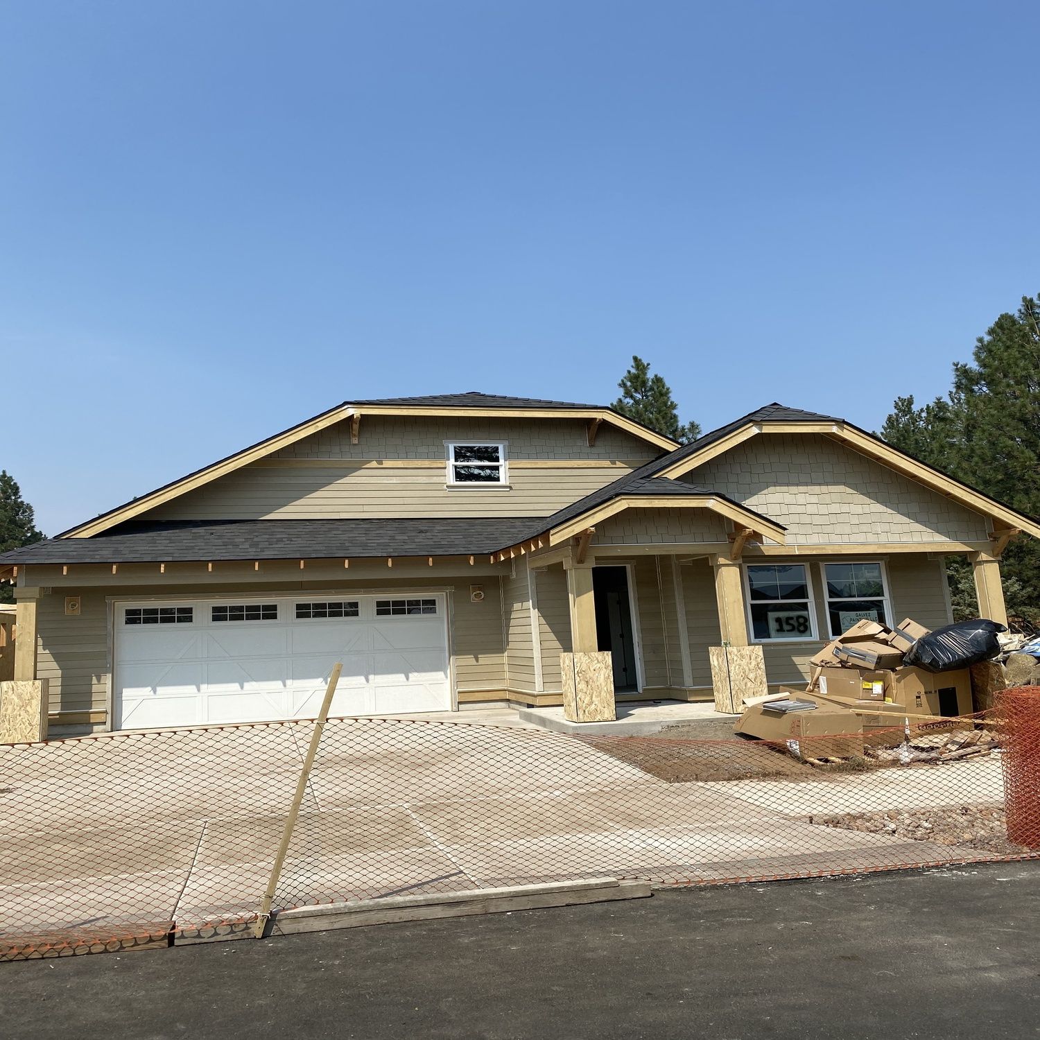 New house under construction with beige siding, white garage door, and a driveway in front