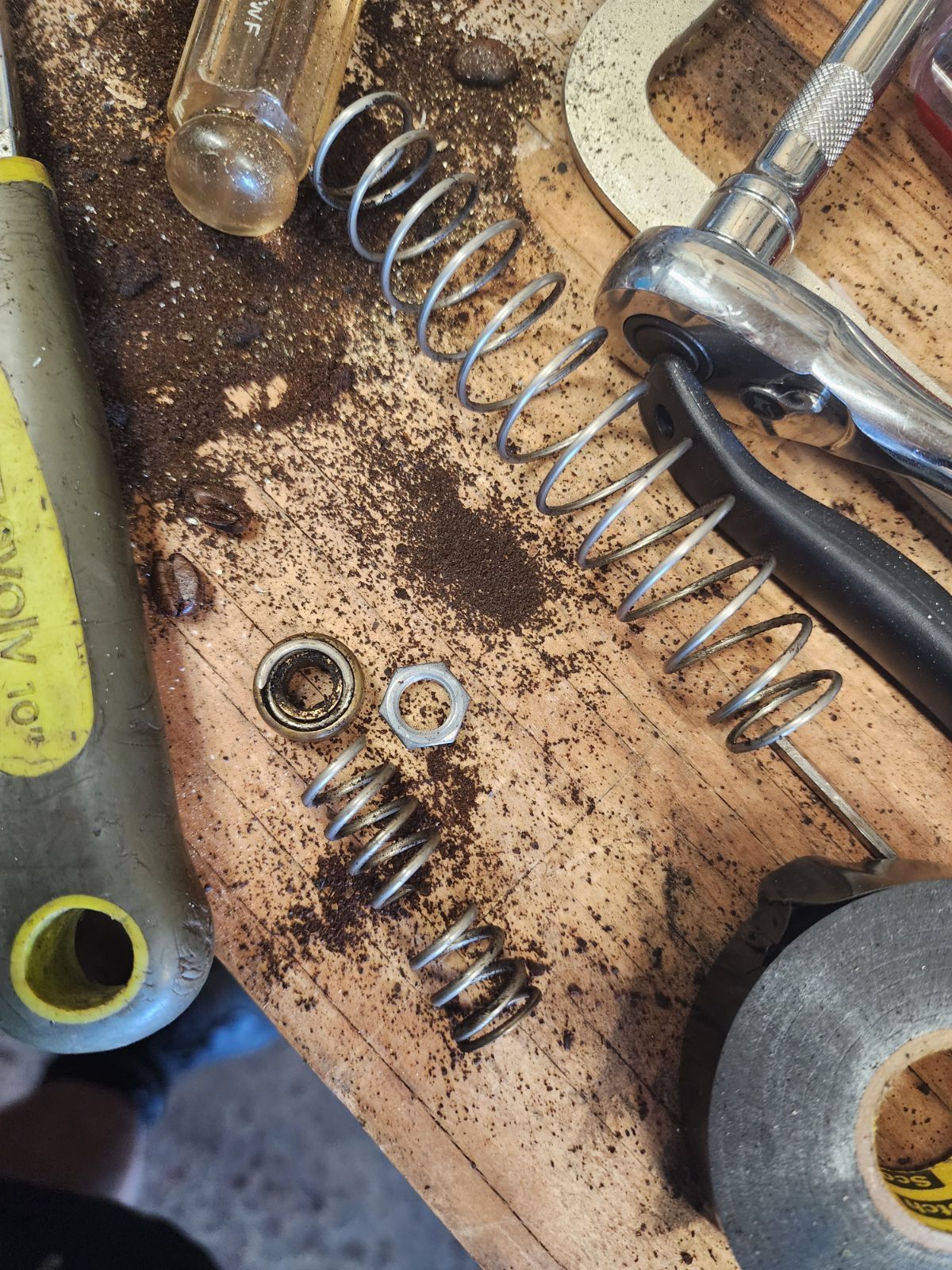 Scattered metal springs and washers on a dirty workbench with tools nearby