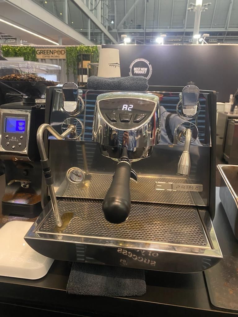 Chrome espresso machine with grinder at a coffee expo display